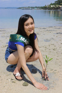 Portrait of smiling young woman sitting on beach