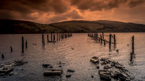 Wooden posts on beach against sky