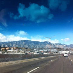 Road leading towards mountains against cloudy sky