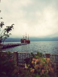 Ship in sea against cloudy sky