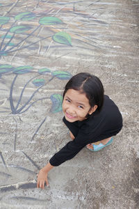 Portrait of smiling girl crouching on footpath