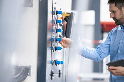 Businessman with tablet pc operating machine in factory