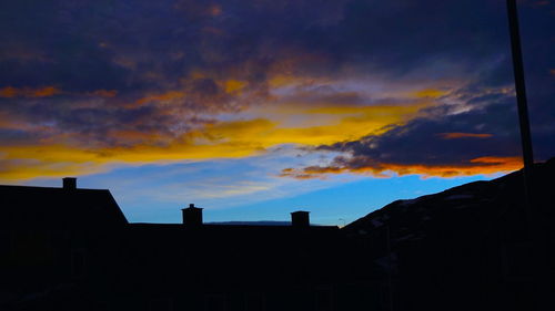 Low angle view of silhouette buildings against sunset sky