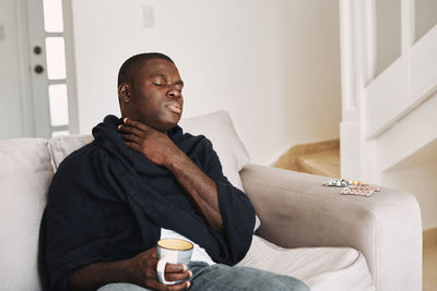 Mid adult man with coffee cup sitting on sofa