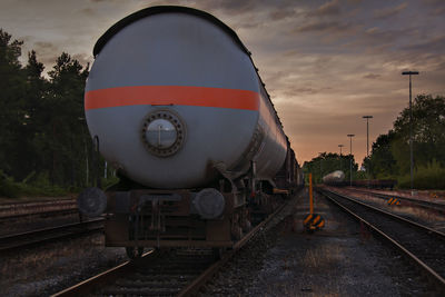 Train by railroad tracks against sky during sunset