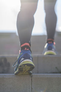 Low section of athlete wearing shoes walking on staircase