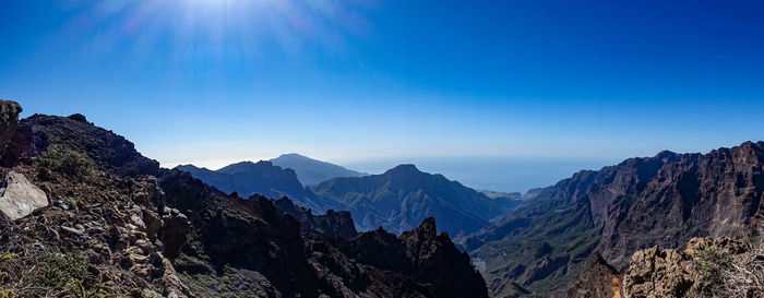 Panoramic view of mountains against blue sky