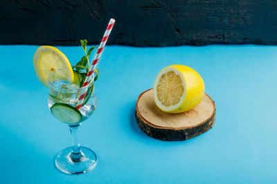 Cocktail cucumber water with lemon and mint in a glass on a napkin on a blue background near lemon 