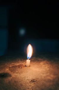 Close-up of lit candle in the dark