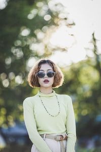 Portrait of young woman wearing sunglasses standing in park