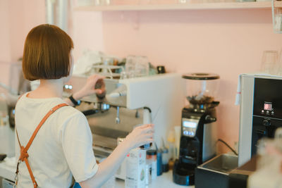 Asian woman owner brewing ice dalgona with coffee maker background