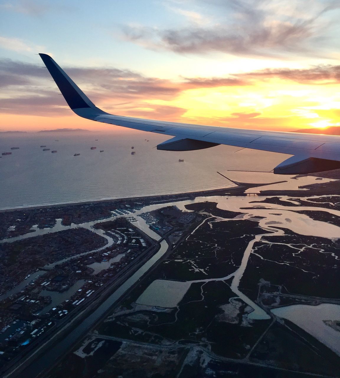 CROPPED IMAGE OF AIRPLANE FLYING OVER SEA AT SUNSET