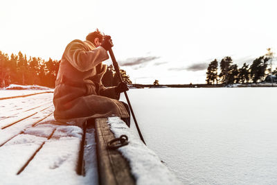 Man photographing on snow covered landscape against sky