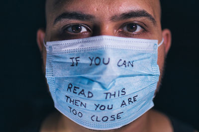 Close-up portrait of man wearing mask against black background