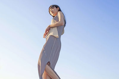 Low angle view of woman standing against clear sky