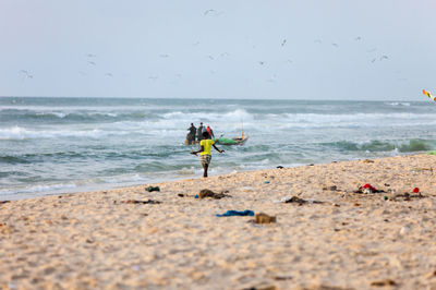 People at beach against sky