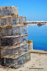 Stack of lobster cages at sea against clear blue sky