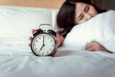 Woman with alarm clock sleeping on bed
