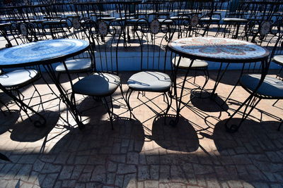 High angle view of empty chairs and tables at sidewalk cafe