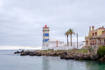 Lighthouse by sea against sky