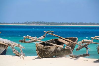 Outrigger canoe moored on beach against clear blue sky