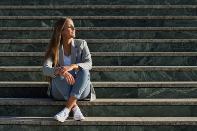 Full length of woman sitting on staircase