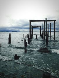 Pier on sea against cloudy sky