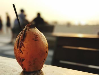 Close-up of coconut with drinking straw on promenade during sunset