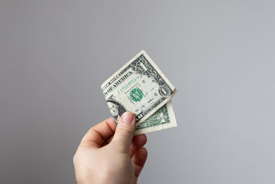 Cropped hand holding paper currency against gray background
