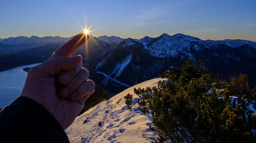 Cropped hand pointing against sky during sunset