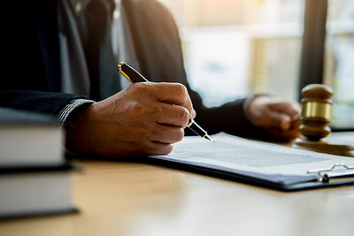 Midsection of man reading book on table