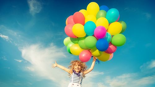 Low angle view of balloons flying against sky