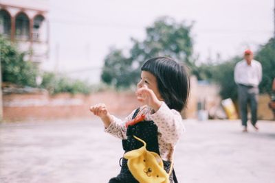 Young woman looking away while standing on road in city