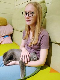 Beautiful young woman with cat sitting at home