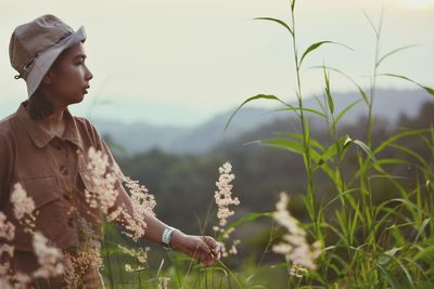 Side view of young woman looking away on field