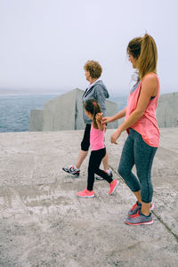 Multi-generation family walking on pier by sea against sky