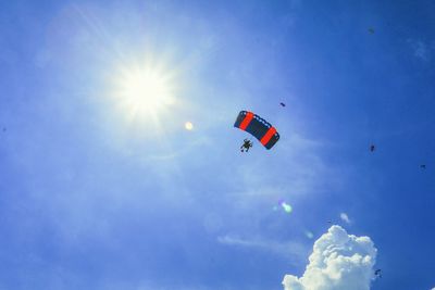 Low angle view of paragliding flying in sky during air show festival 