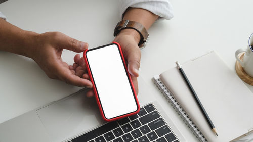 Cropped hand of man using mobile phone on table