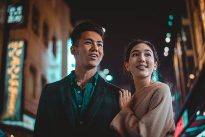 Smiling couple standing on street in city at night