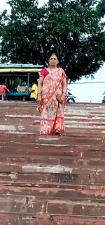 Full length of woman sitting on tree