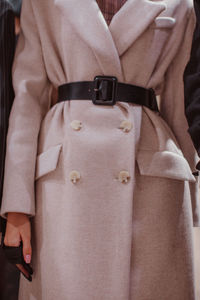 Black leather belt, beige long coat. women's fashion and stylish accessories. autumn winter fashion