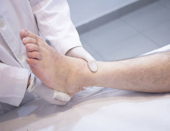 Midsection of doctor examining patient leg in hospital