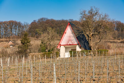 House on field by trees against sky