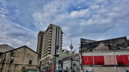 Low angle view of skyscrapers against cloudy sky