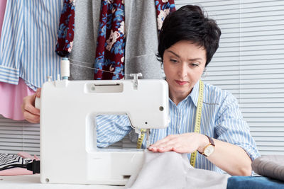 Craftswoman sewing textile on machine at workshop