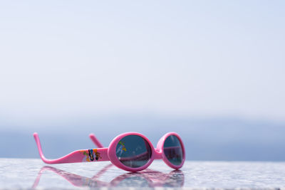 Close-up of sunglasses on beach against sky