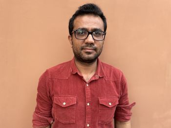 Portrait of young man standing against yellow wall