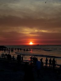 Silhouette people on beach against sky during sunset