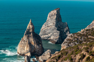 Rock formations in sea against blue sky