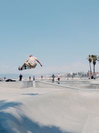 Rear view of man skateboarding against sky